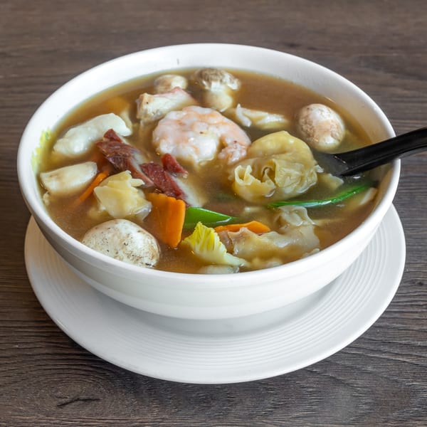 A bowl of Go China Restaurant's Chinese soup with shrimp, mushrooms, wontons, and vegetables.