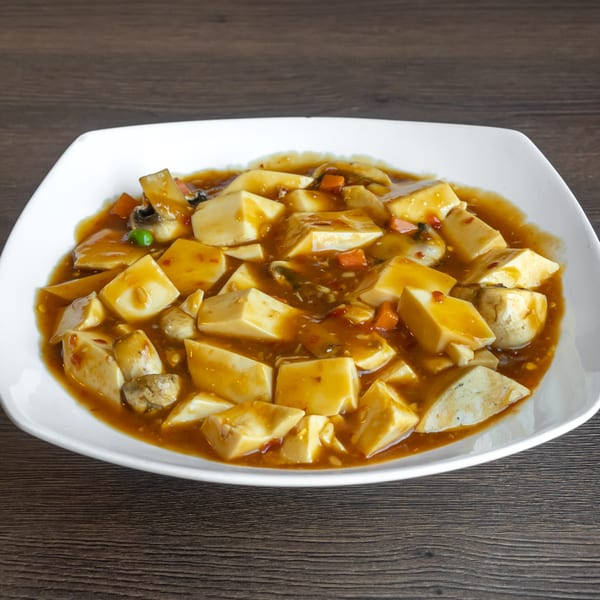 A white square plate filled with Go China Restaurant's tofu and vegetables in a rich brown sauce.