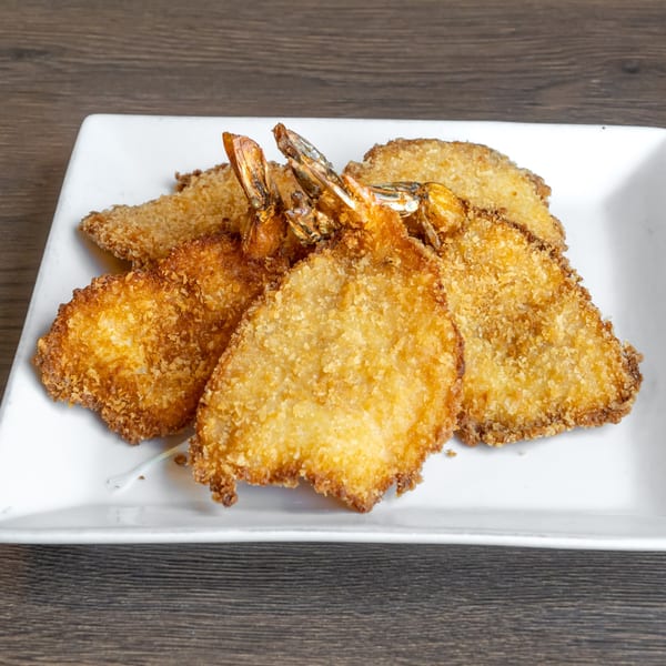 Golden-brown fried shrimp and fish fillets, breaded and crispy, served on a white rectangular plate.